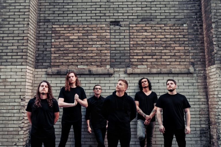 The band members of The Contortionist standing against a brick wall.