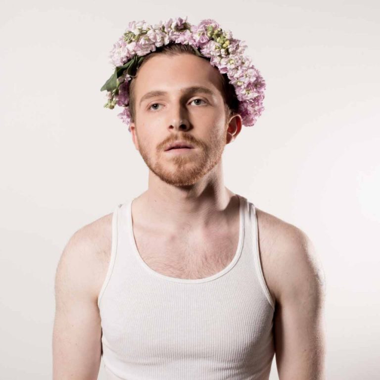 A portrait of Zander Hawley with flowers wrapped around his head.
